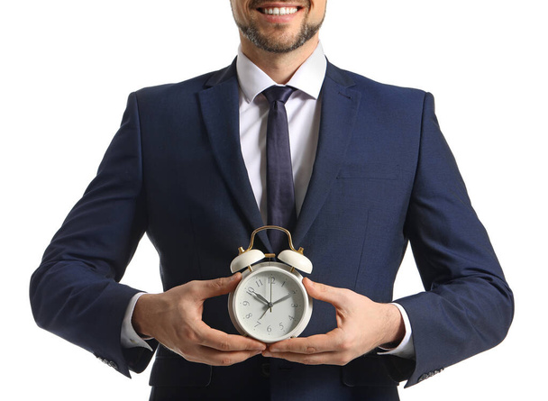 ホワイトを背景に目覚まし時計を持つビジネスマン。時間管理の考え方 - 写真・画像