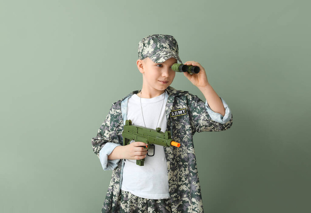 Lindo soldadito con binocular y pistola de juguete sobre fondo de color
 - Foto, imagen