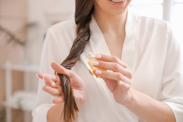 Young woman using cosmetics for hair at home, closeup - Fotoğraf, Görsel
