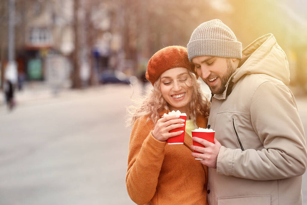 Happy young couple drinking hot cocoa outdoors - Фото, зображення