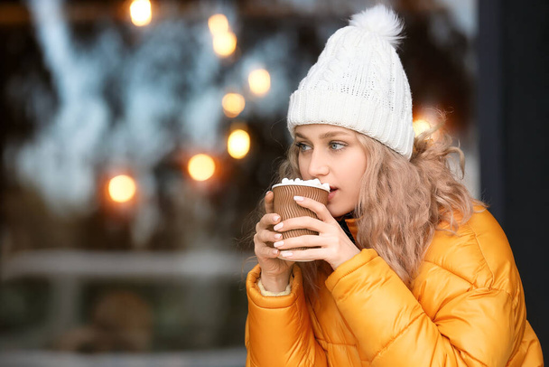 Beautiful young woman drinking hot cocoa outdoors - Photo, Image
