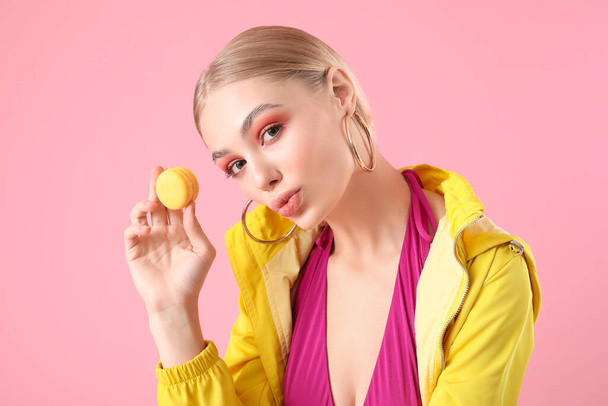 Beautiful fashionable woman with macaron on color background - Photo, Image