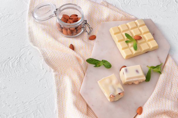 Makea valkoinen suklaa pähkinöillä ja mintulla pöydällä
 - Valokuva, kuva