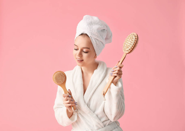 Beautiful young woman with brushes for bath on color background - 写真・画像