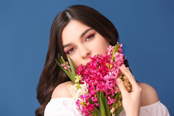 Красивая молодая женщина с гиацинтовыми цветами на цветном фоне - Фото, изображение
