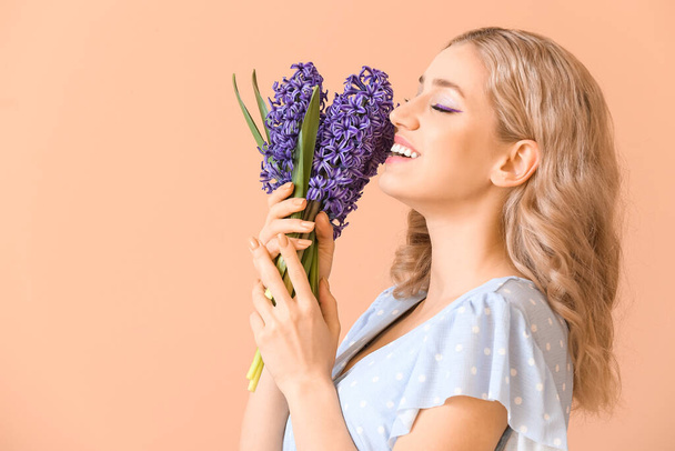 Schöne junge Frau mit Hyazinthenblüten auf farbigem Hintergrund - Foto, Bild