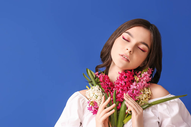 Beautiful young woman with hyacinth flowers on color background - 写真・画像