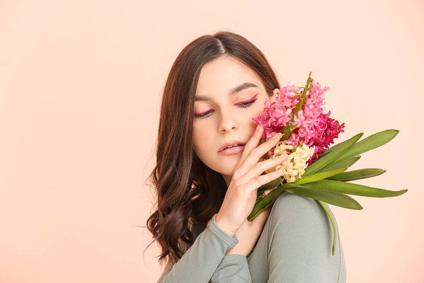 Beautiful young woman with hyacinth flowers on color background - 写真・画像