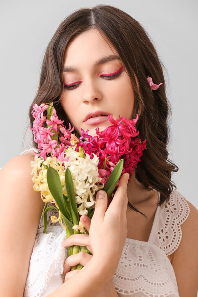 Hermosa mujer joven con flores de jacinto sobre fondo claro - Foto, imagen