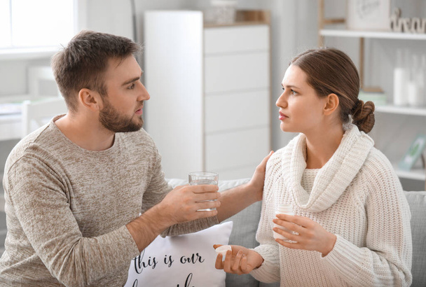 A férfi vizet ad a feleségének, aki otthon fog gyógyszert szedni. - Fotó, kép