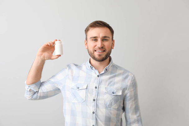 Young man with pills on light background - Photo, image