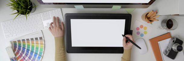 Vue aérienne du graphiste féminin dessinant sur tablette graphique maquette et travaillant sur ordinateur dans la salle de bureau
 - Photo, image