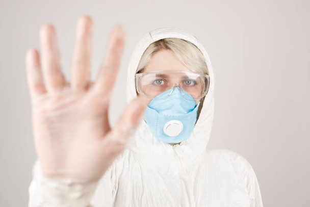 Ein Mädchen in Schutzanzug und Atemschutzmaske, um die Gesundheit vor Viren, Epidemien und Infektionskrankheiten zu schützen. Neue Covid-19. Coronavirus-Pandemie-Konzept. Stoppt das Virus. Nahaufnahme. - Foto, Bild