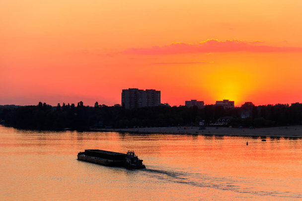 Rebocador empurrando uma pesada barcaça longa no rio Dnieper ao pôr do sol - Foto, Imagem