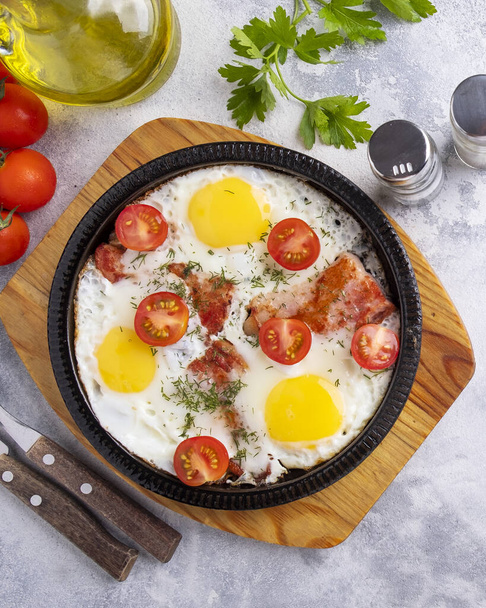 Tasty breakfast with fried eggs, bacon and vegetables on a frying pan. Morning breakfast concept. Closeup. Top view - Foto, immagini