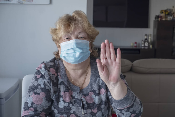 Здорова літня жінка у блакитній медичній захисній масці демонструє стоп жестів. Спалах коронавірусу - Фото, зображення