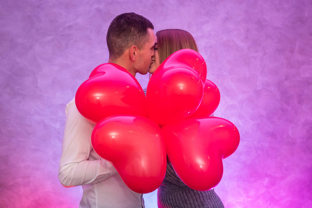 Portrait de jeune couple avec des ballons à air rouge en forme de coeur. Concept de célébration de la Saint-Valentin
 - Photo, image