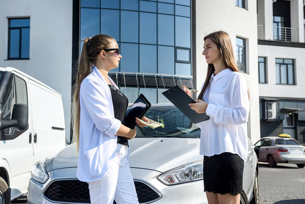 Rent or car buy concept. Two women with dollar bundle posing near car - Foto, immagini