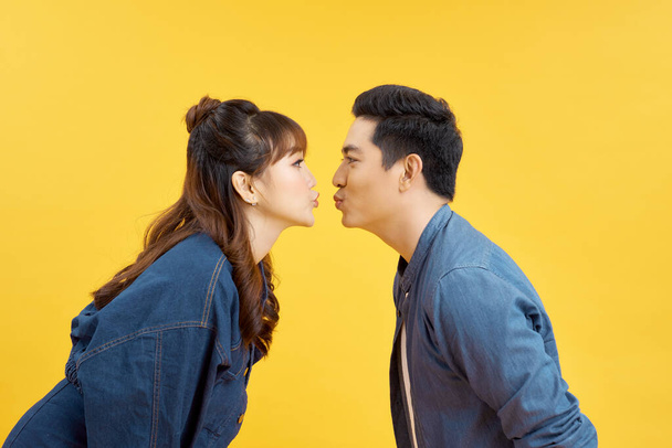 Profile dziewczyny i chłopaka dając sobie powietrzny pocałunek na żółto - Zdjęcie, obraz