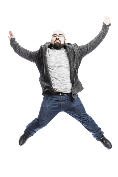 A bald man in glasses emotionally jumps. White background. Vertical. - Foto, afbeelding