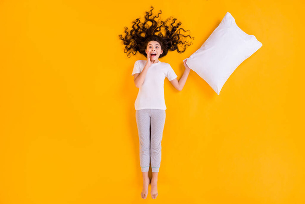 Full body high angle above flat lay view photo of beautiful little lady lying morning exciting feelings emotions hold white pillow wear pajama isolated yellow color background - Photo, image