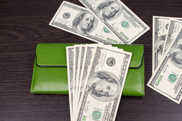 Geldbörse mit Geld auf braunem Hintergrund. Ein Pack Dollars im Portemonnaie. Banknoten einhundert Dollar - Foto, Bild