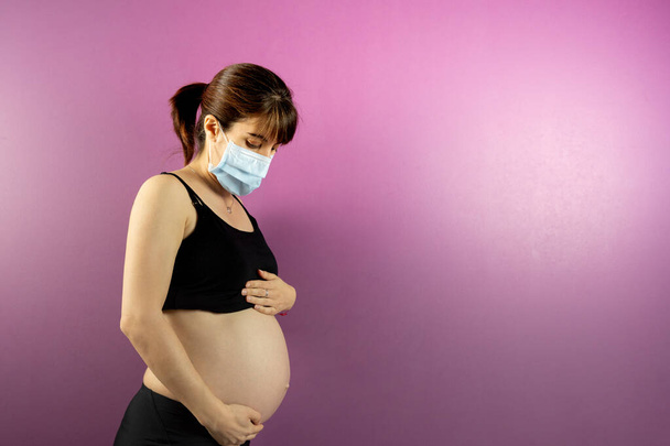 Zwangere vrouw bezorgd voor kind met masker vanwege Coronavirus COVID-19 - Foto, afbeelding