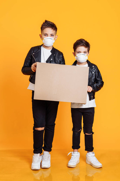 Covid-19 contra los niños. Retrato de dos chicos con máscaras protectoras, sosteniendo un cartel sin palabras. Aislamiento del coronovirus
. - Foto, imagen