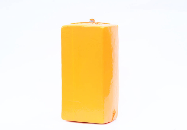 Beyaz arkaplanda izole edilmiş sarı vakum paketindeki peynir bloğu. - Fotoğraf, Görsel