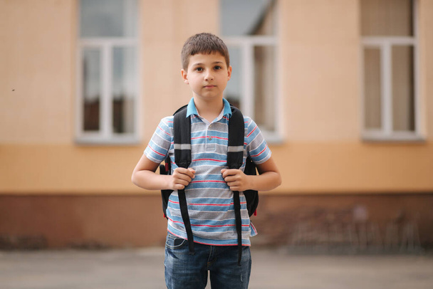 Милый маленький мальчик с рюкзаком идет домой после уроков.
 - Фото, изображение