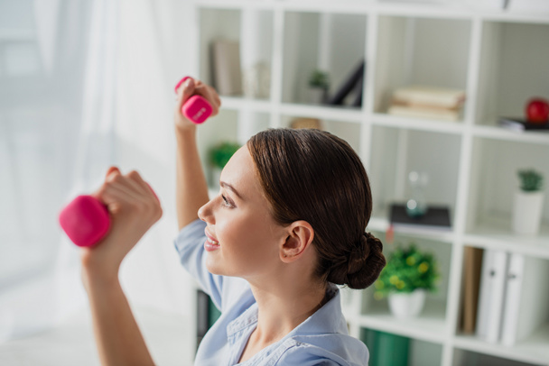 beautiful happy businesswoman training with dumbbells in office - 写真・画像
