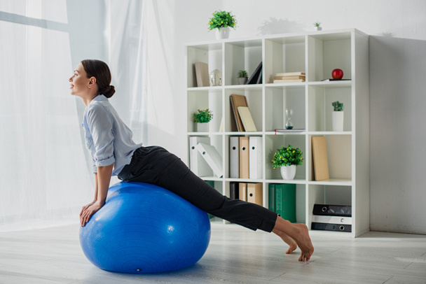 happy businesswoman stretching on fitness balls in office - Photo, Image