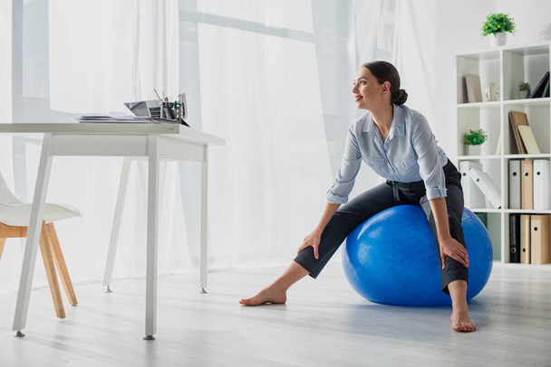 smiling businesswoman exercising on fitness balls in office - 写真・画像