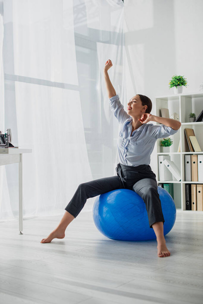 beautiful happy businesswoman stretching on fitness balls in office - Photo, Image