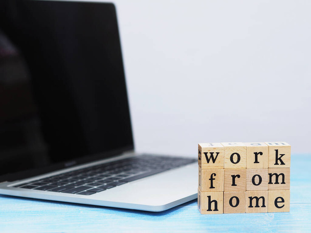 Wooden blocks with alphabet letter Work from home and notebook computer on blue table with copy space. Work from home concept.  - 写真・画像