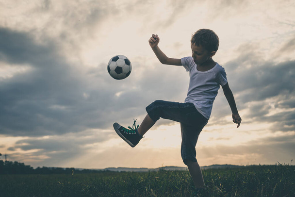 Niño jugando en el campo con pelota de fútbol. Concepto de deporte
. - Foto, Imagen