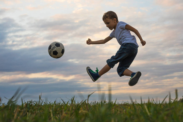 Niño jugando en el campo con pelota de fútbol. Concepto de deporte
. - Foto, imagen