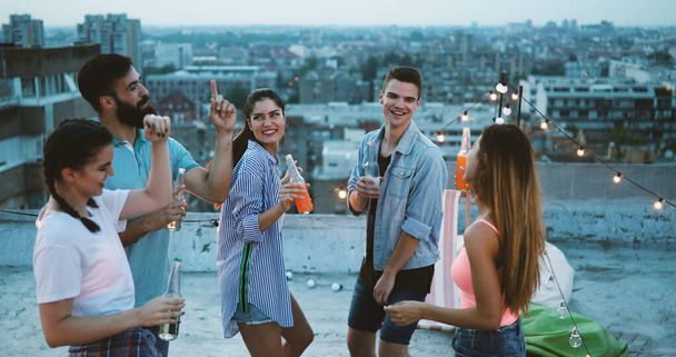Happy friends having party on top of the roof . Fun, summer, city lifestyle and friendship concept - Foto, imagen