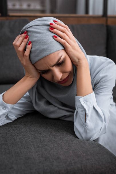 depressieve moslim vrouw aanraken hijab en huilen in de woonkamer, huiselijk geweld concept   - Foto, afbeelding