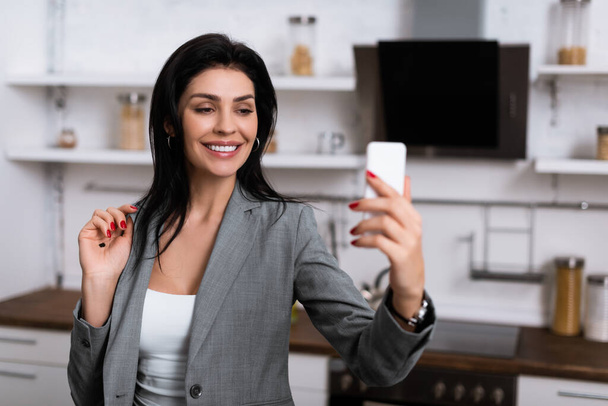 enfoque selectivo de la mujer de negocios sonriente con punto negro en la palma tomando selfie, concepto de violencia doméstica
  - Foto, Imagen