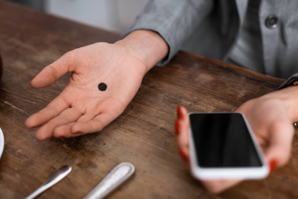 vista recortada de la mujer con punto negro en la palma celebración de teléfono inteligente con pantalla en blanco, concepto de violencia doméstica
  - Foto, Imagen