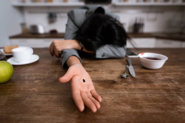 selektiver Fokus der Geschäftsfrau, die Hand mit schwarzem Punkt auf der Handfläche zeigt, während sie Gesicht bedeckt, Konzept häuslicher Gewalt  - Foto, Bild
