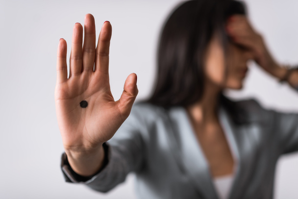 selective focus of businesswoman with black dot on palm isolated on white, domestic violence concept  - Photo, Image
