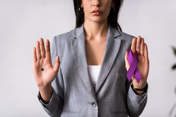 vista recortada de la mujer de negocios con punto negro en la palma de la mano que sostiene la cinta púrpura en blanco, concepto de violencia doméstica
  - Foto, imagen