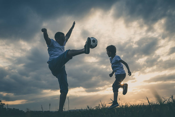 Father and young little boy playing in the field  with soccer ball. Concept of sport. - Foto, Imagen