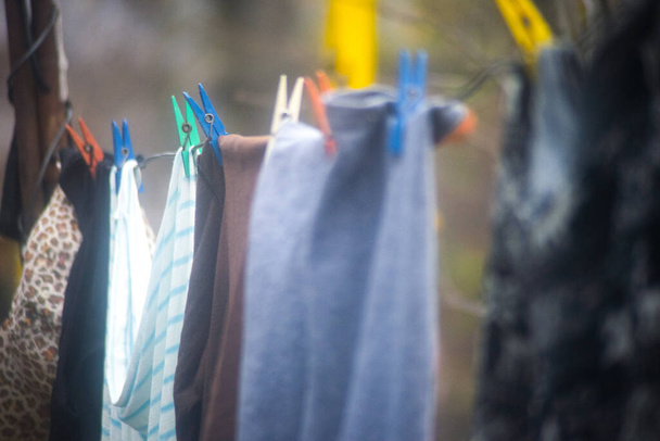 Одежда, высушенная на солнце на стиральной линии с пластиковыми прищепками. Селективный фокус
. - Фото, изображение