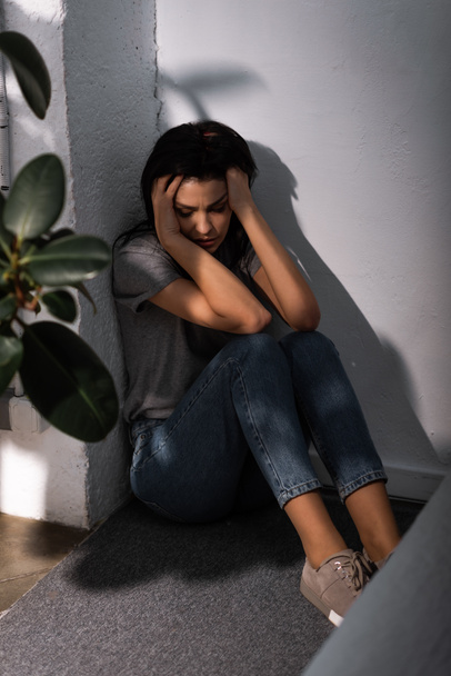 自宅の床に座っている顔にあざを持つ恐怖の女性の選択的な焦点,家庭内暴力の概念  - 写真・画像