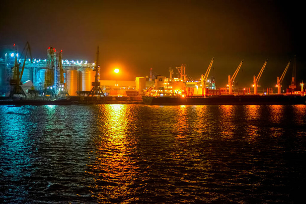 Μαύρη Θάλασσα. βαρέα ανυψωτικά πλοία αγκυροβολημένα στη θάλασσα. στο παρασκήνιο είναι κατοικίες και εμπορικά κτίρια τη νύχτα - Φωτογραφία, εικόνα