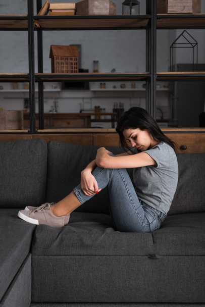 mujer deprimida con moretones en la cara sentada en el sofá en la sala de estar, concepto de violencia doméstica
  - Foto, Imagen
