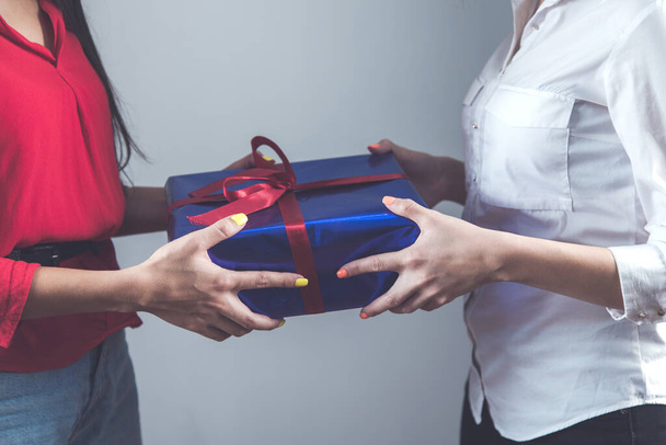 two woman hand holding gift box on grey background - Fotoğraf, Görsel